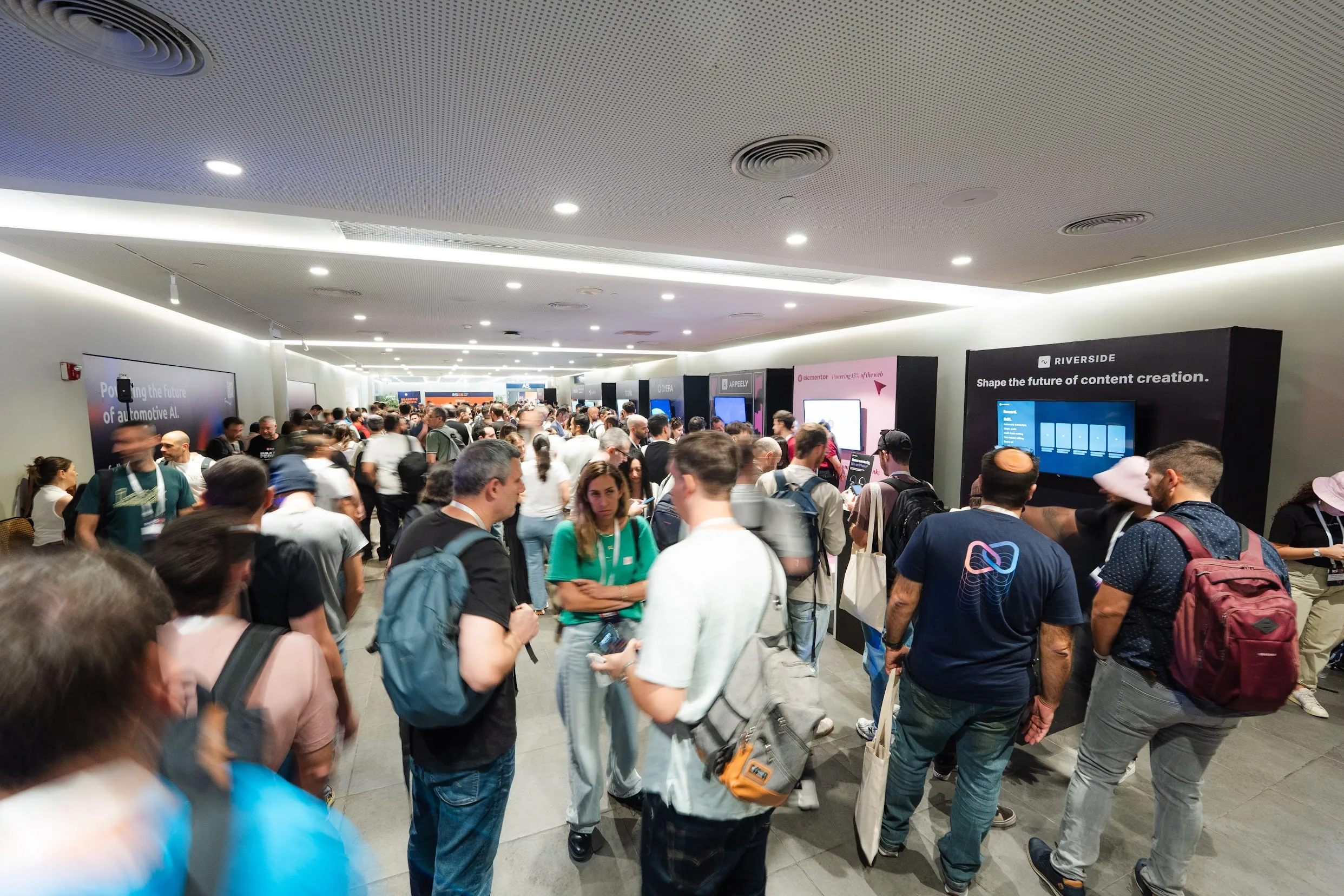 Attendees networking in a busy corridor lined with sponsor branding